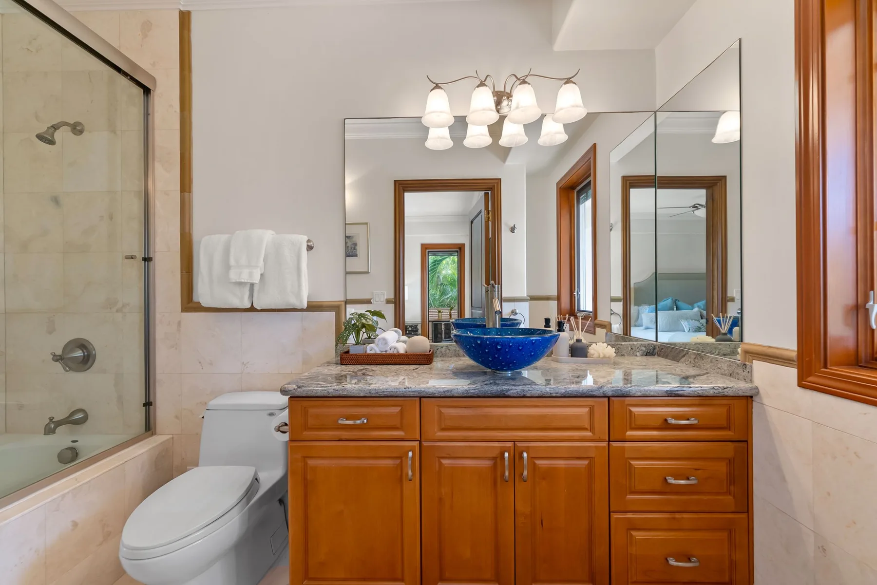 Un baño con un tocador de madera, lavabo azul y ducha de vidrio.