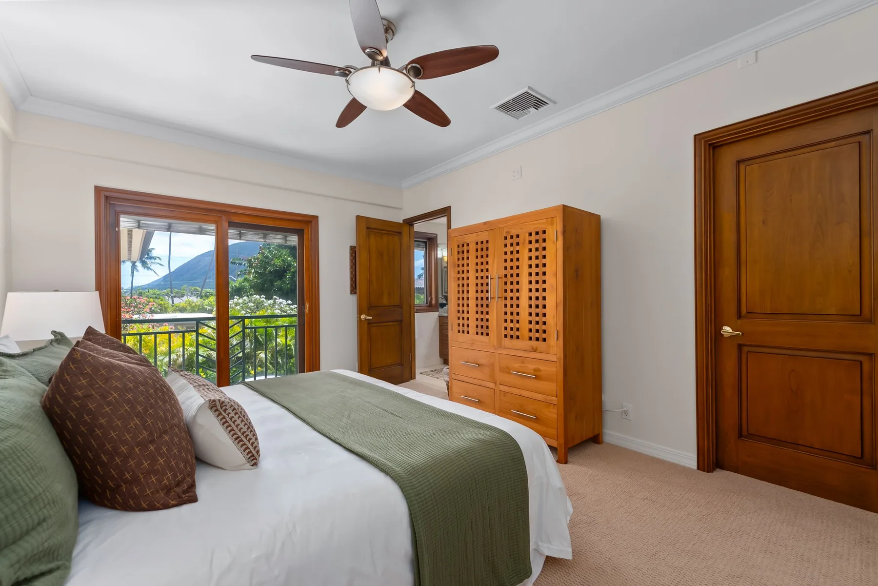 Dormitorio con cama, armario de madera y puertas corredizas de vidrio que dan a un balcón.
