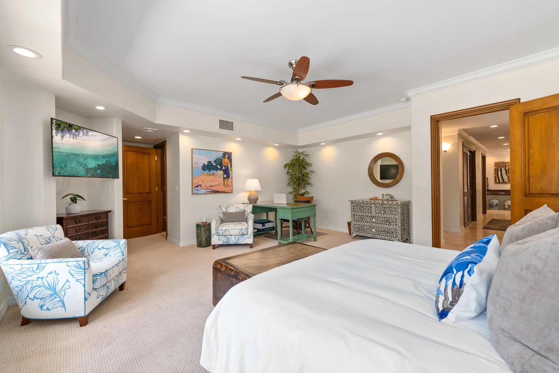 Un dormitorio luminoso con una cama grande, zona de estar y ventilador de techo.