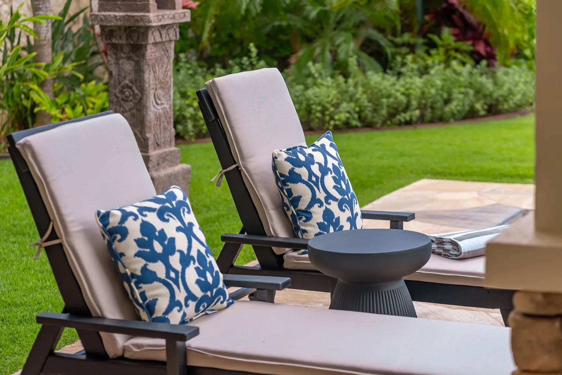 Asientos en un patio exterior con cojines estampados junto a un césped verde.