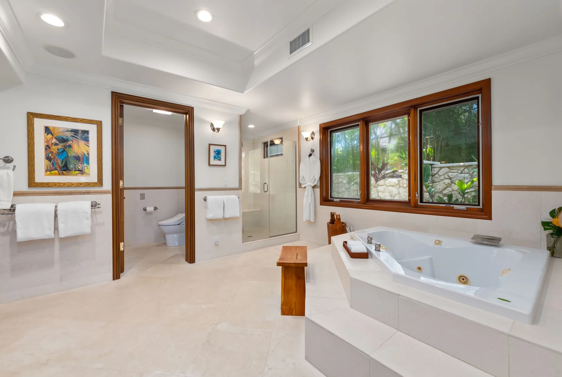 Un baño luminoso cuenta con una bañera junto a grandes ventanas y una ducha de vidrio.