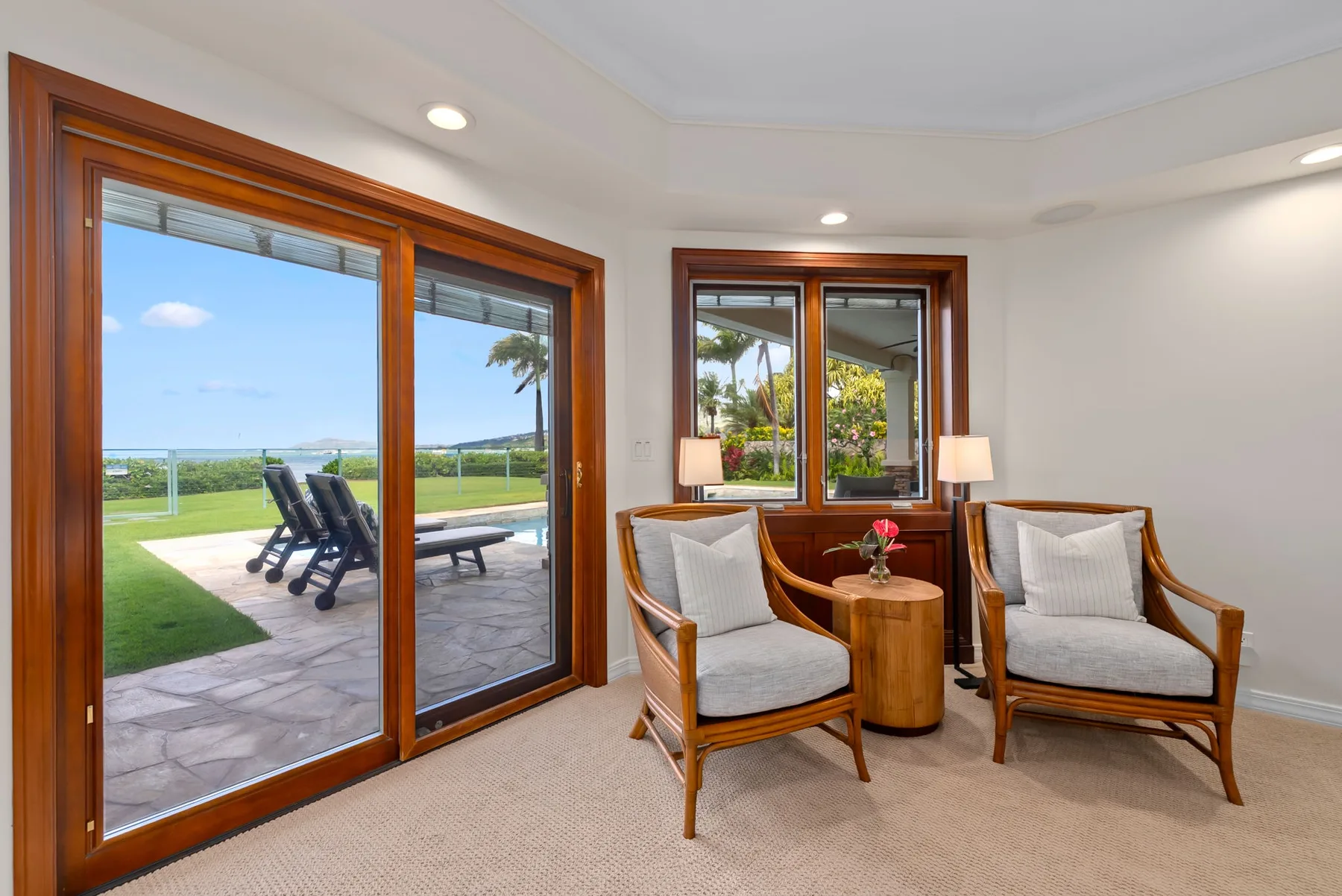 Una luminosa zona de estar con dos sillones junto a grandes ventanas que dan a un patio.