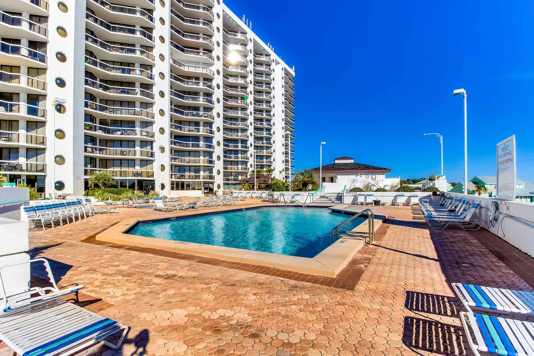 An outdoor swimming pool is surrounded by a paved deck and lounge seating.