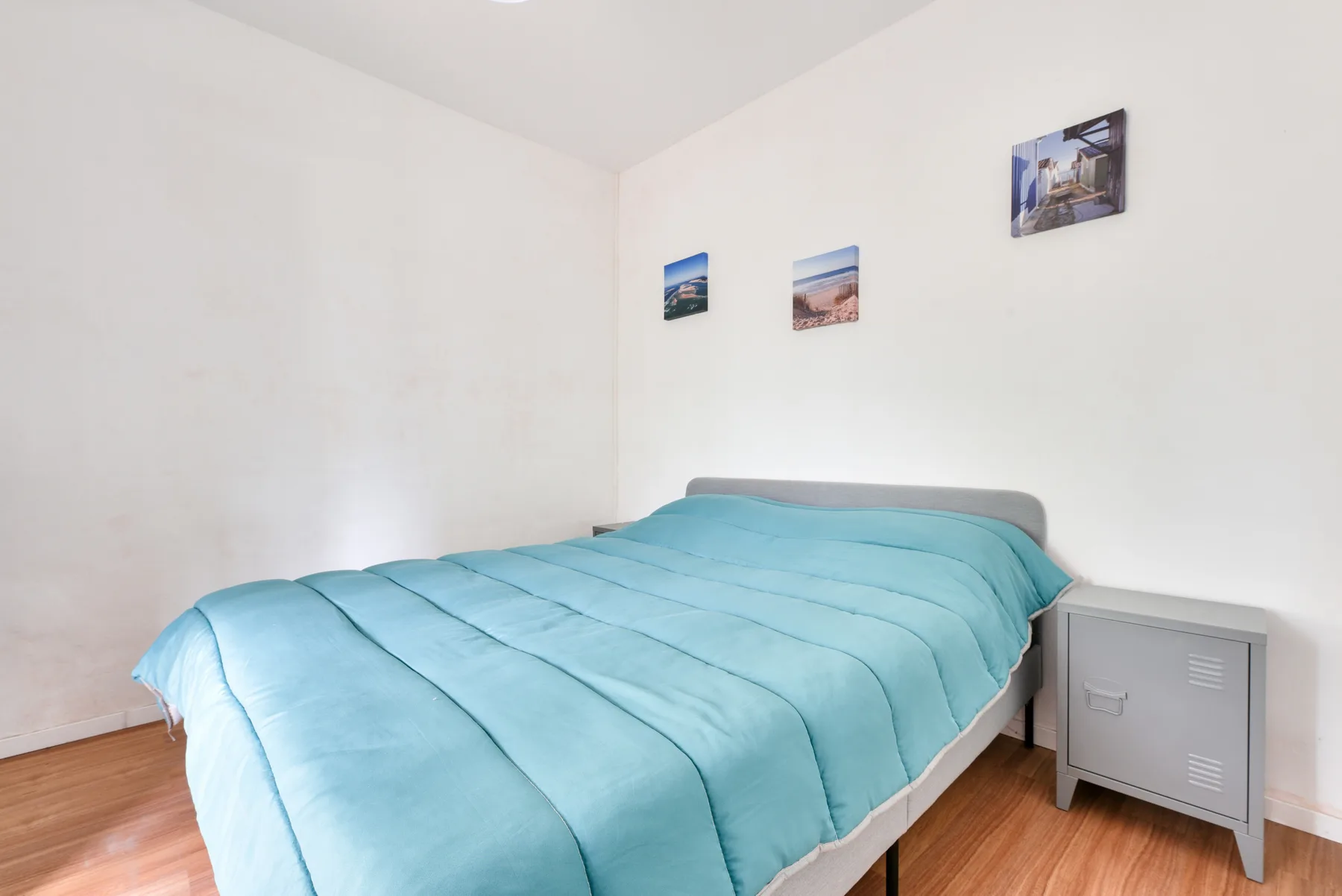 Bedroom with a bed covered by a turquoise comforter.