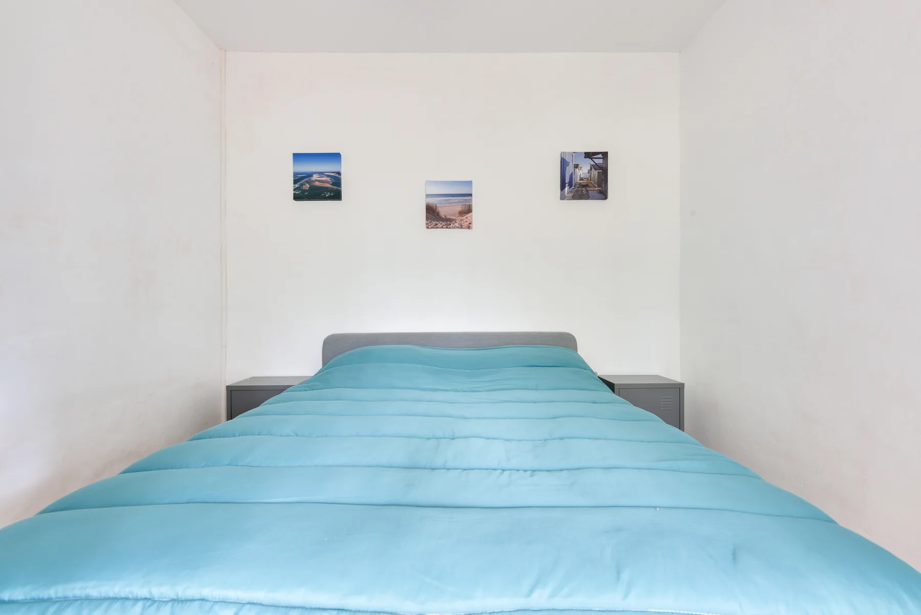 A bedroom with a bed covered in turquoise bedding.