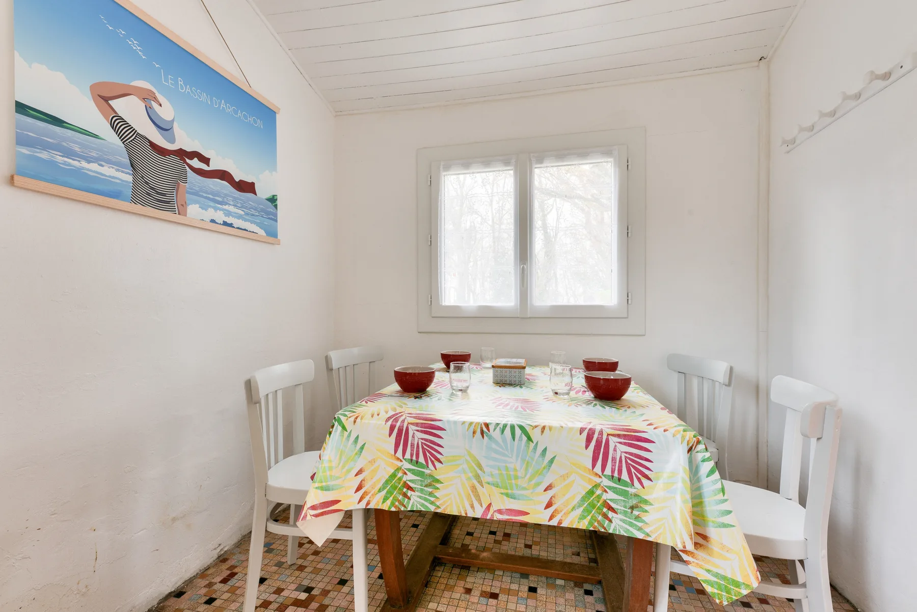 A dining area with a colorful tablecloth and a window.