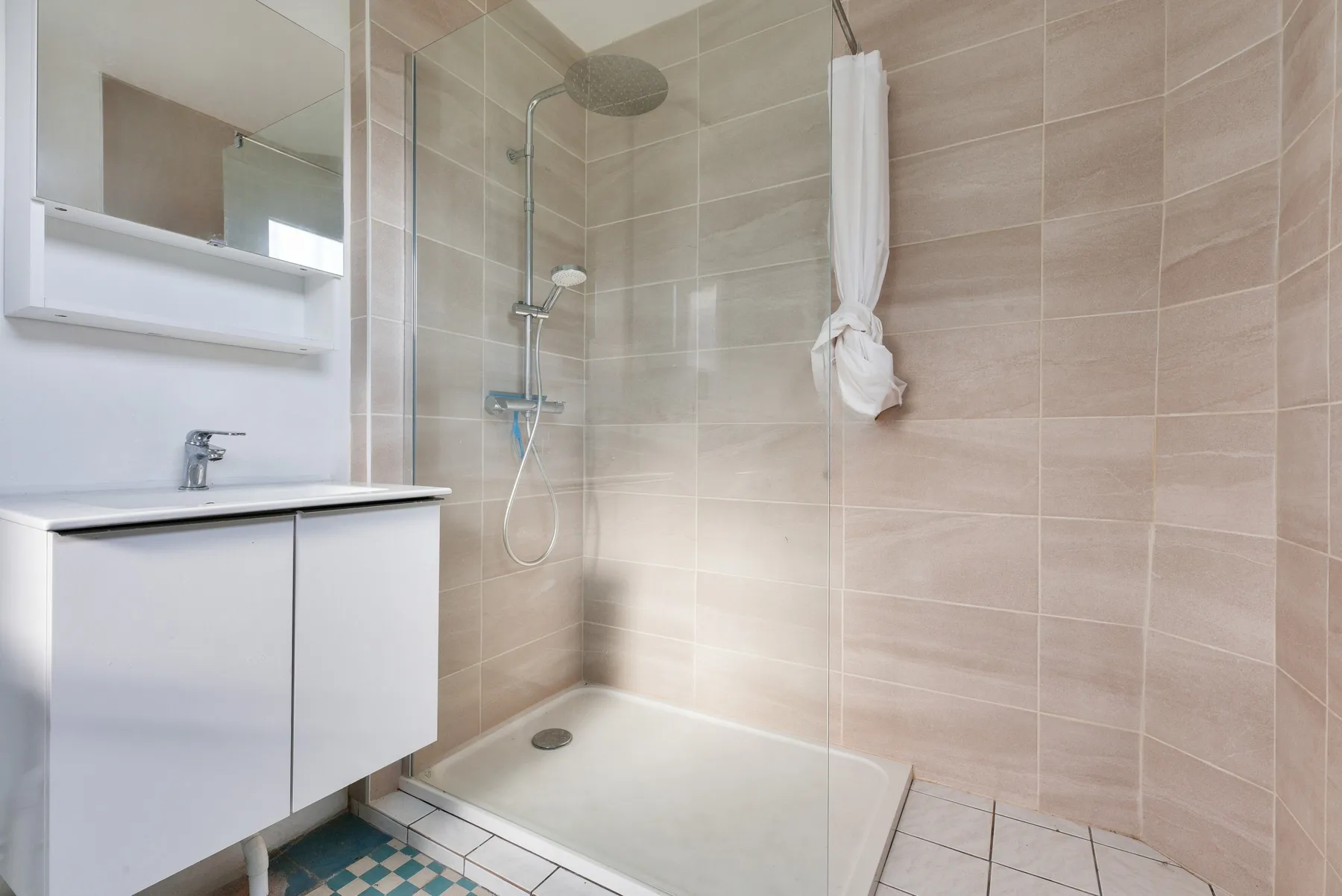 A tiled bathroom with a shower and a white vanity.