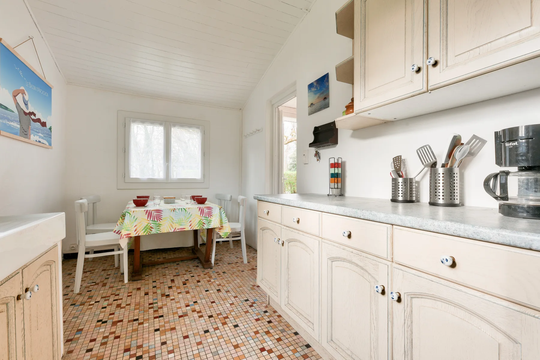 A bright kitchen with white cabinetry and a small dining table.