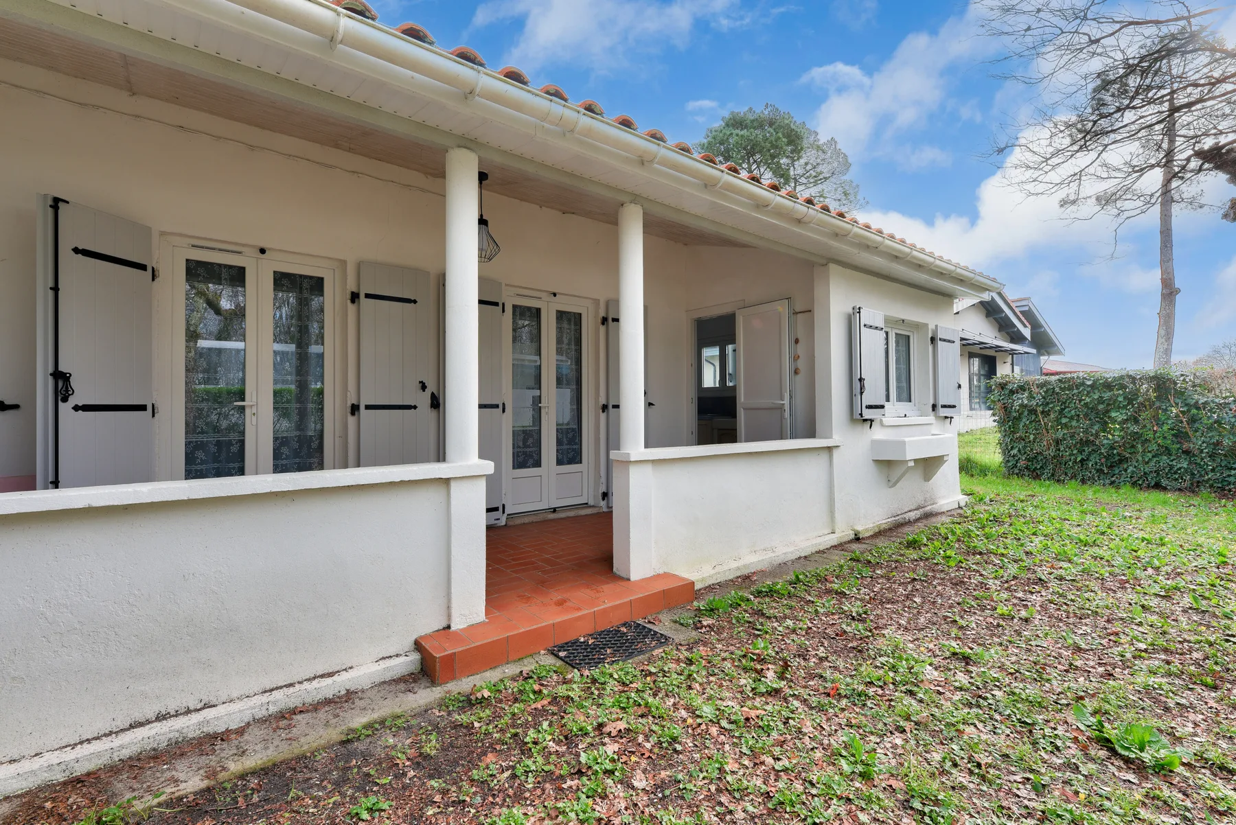 A single-story house with a covered porch and shuttered windows.