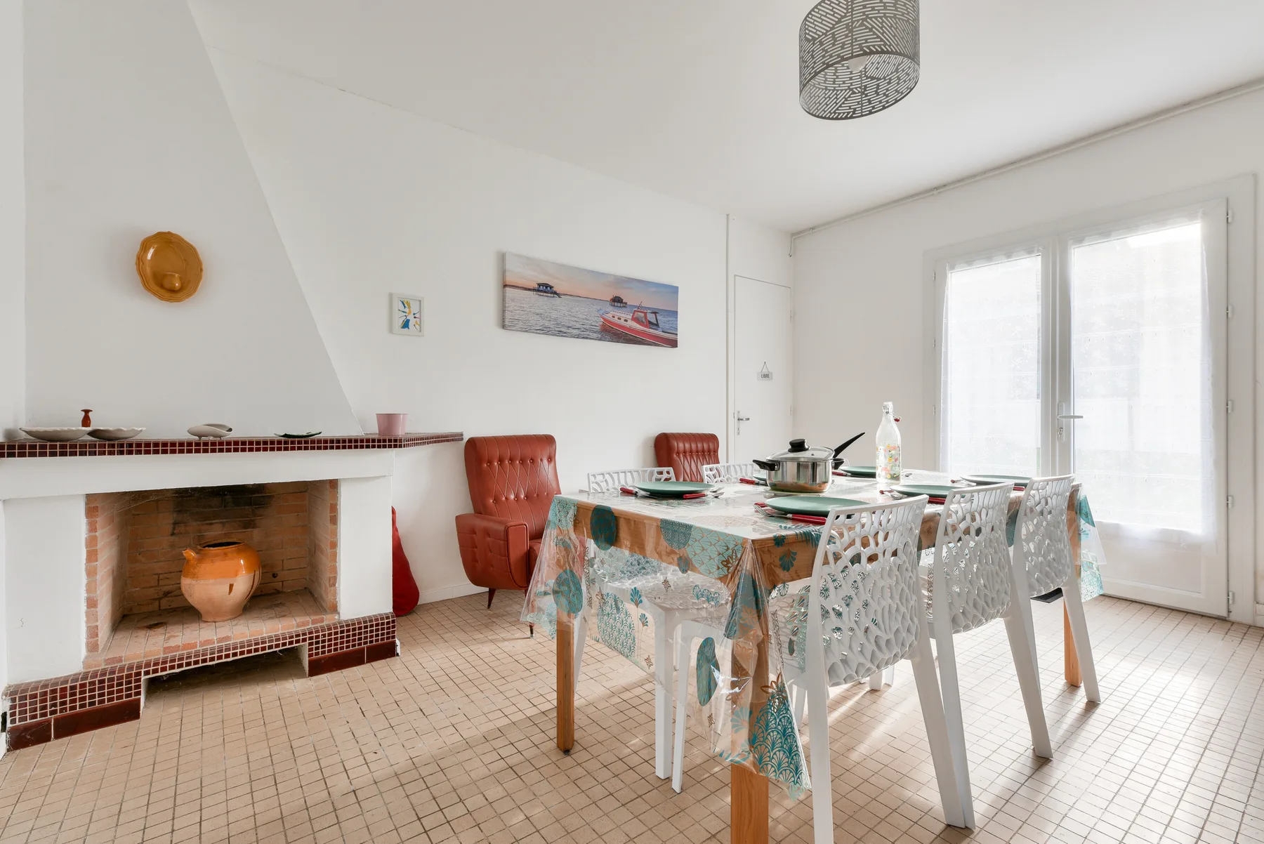 Dining area with a set table beside a fireplace.