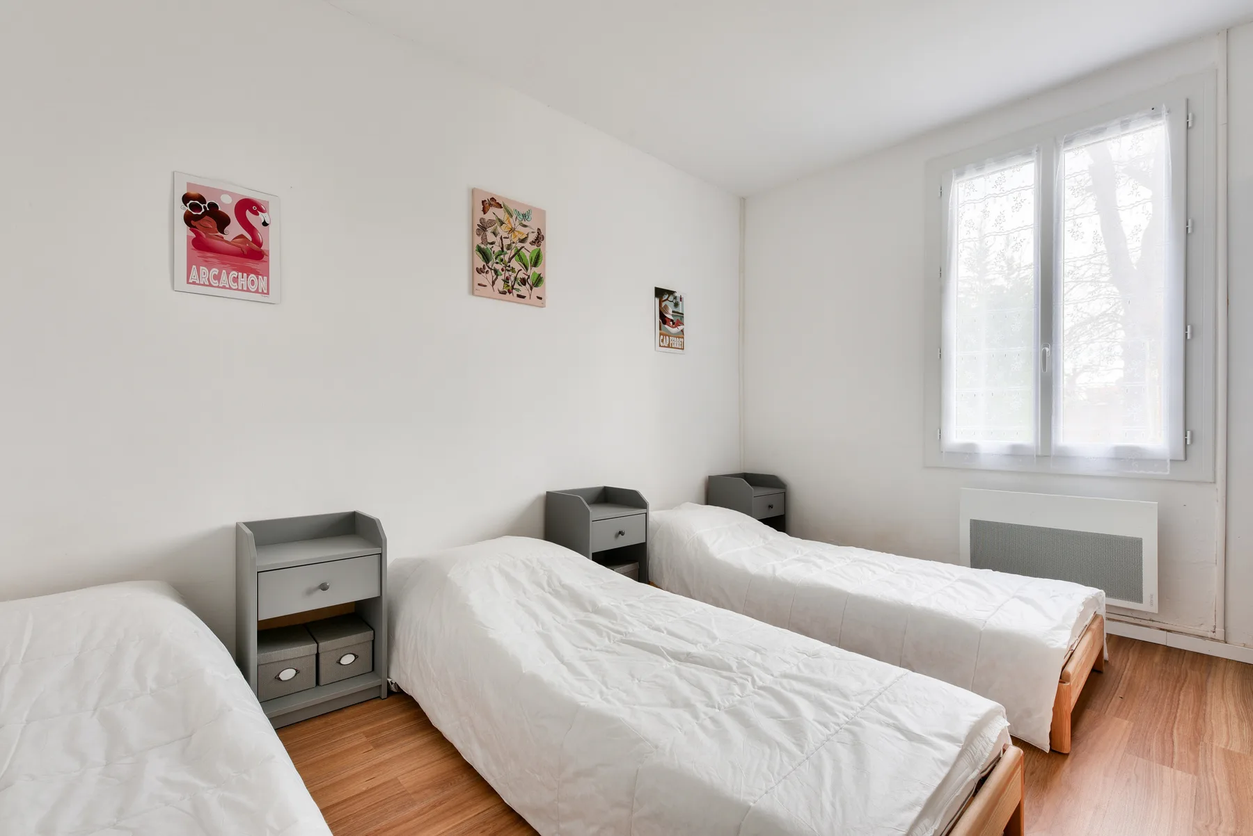 A bright bedroom with several beds and a window.