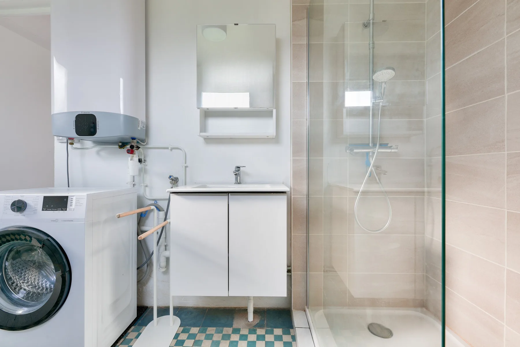 A bathroom with a sink, washing machine, and glass shower.