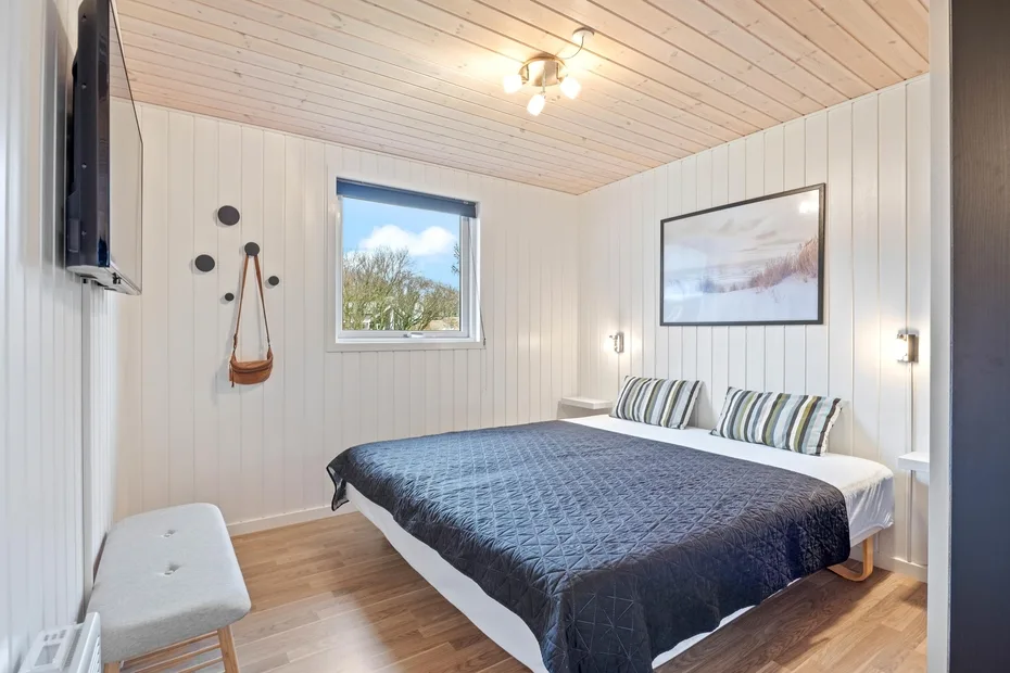 Un dormitorio con una cama grande, almohadas a rayas y una ventana.