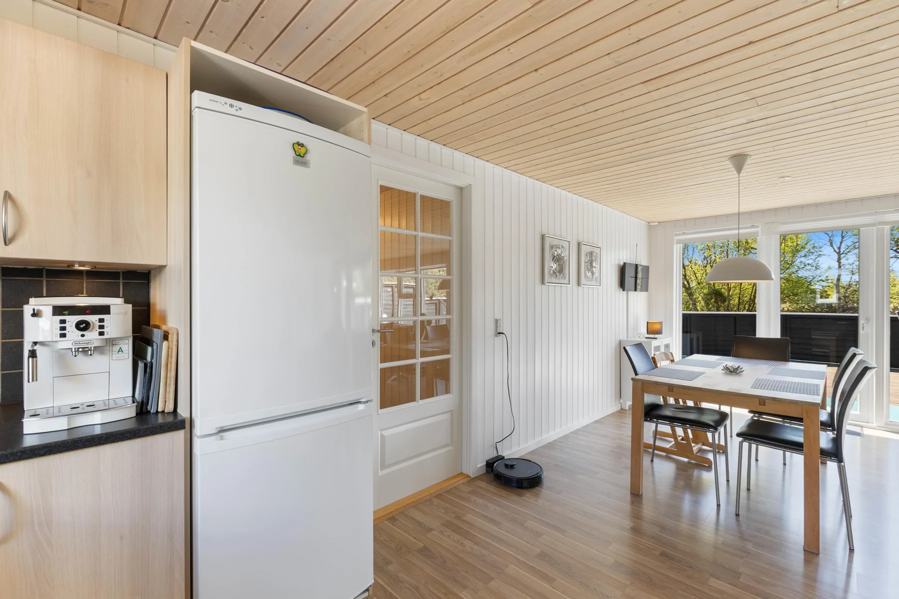 Un comedor luminoso con una mesa y grandes ventanas que dan a la vegetación.