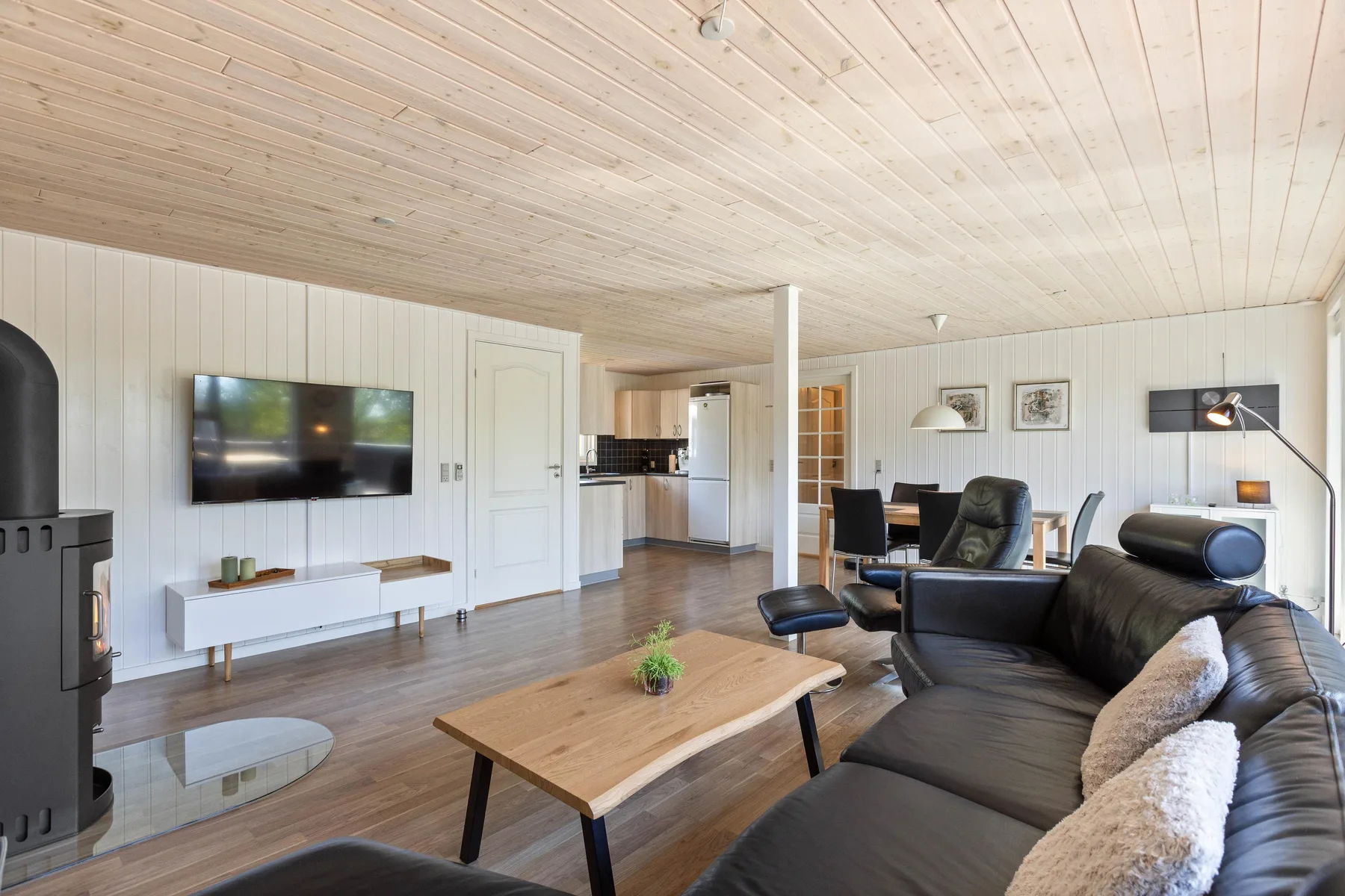 Sala de estar con asientos, un televisor y una zona de cocina abierta.