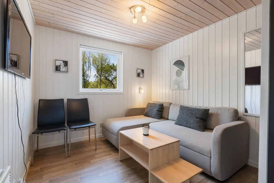 Una sala de estar con un sofá seccional gris y una mesa de centro baja de madera.
