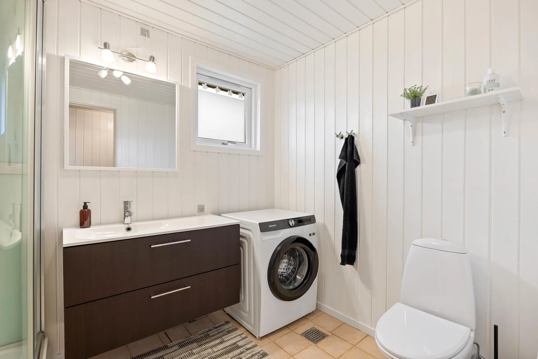 Un baño luminoso con lavabo, lavadora e inodoro.