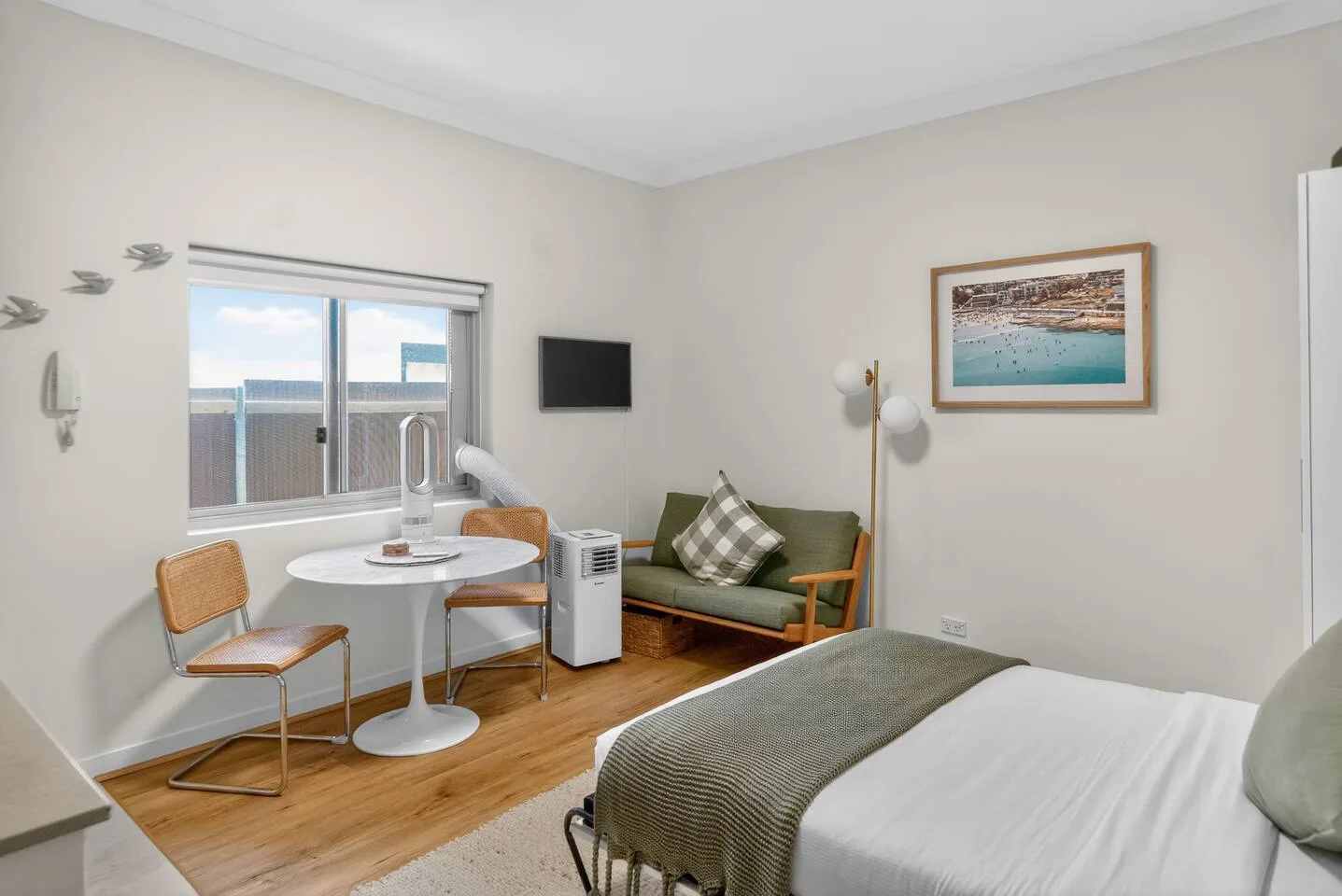 A bedroom with a bed, a small dining table, and a seating area by the window.
