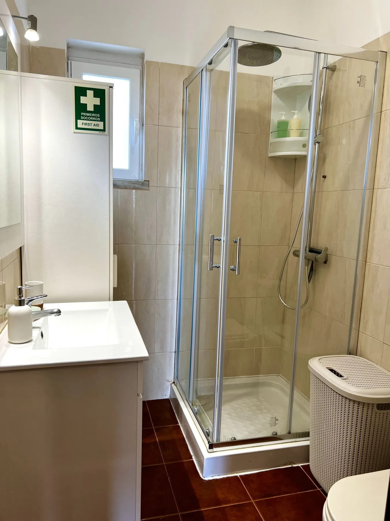 Un baño con una ducha de vidrio, un lavabo y suelo de baldosas.