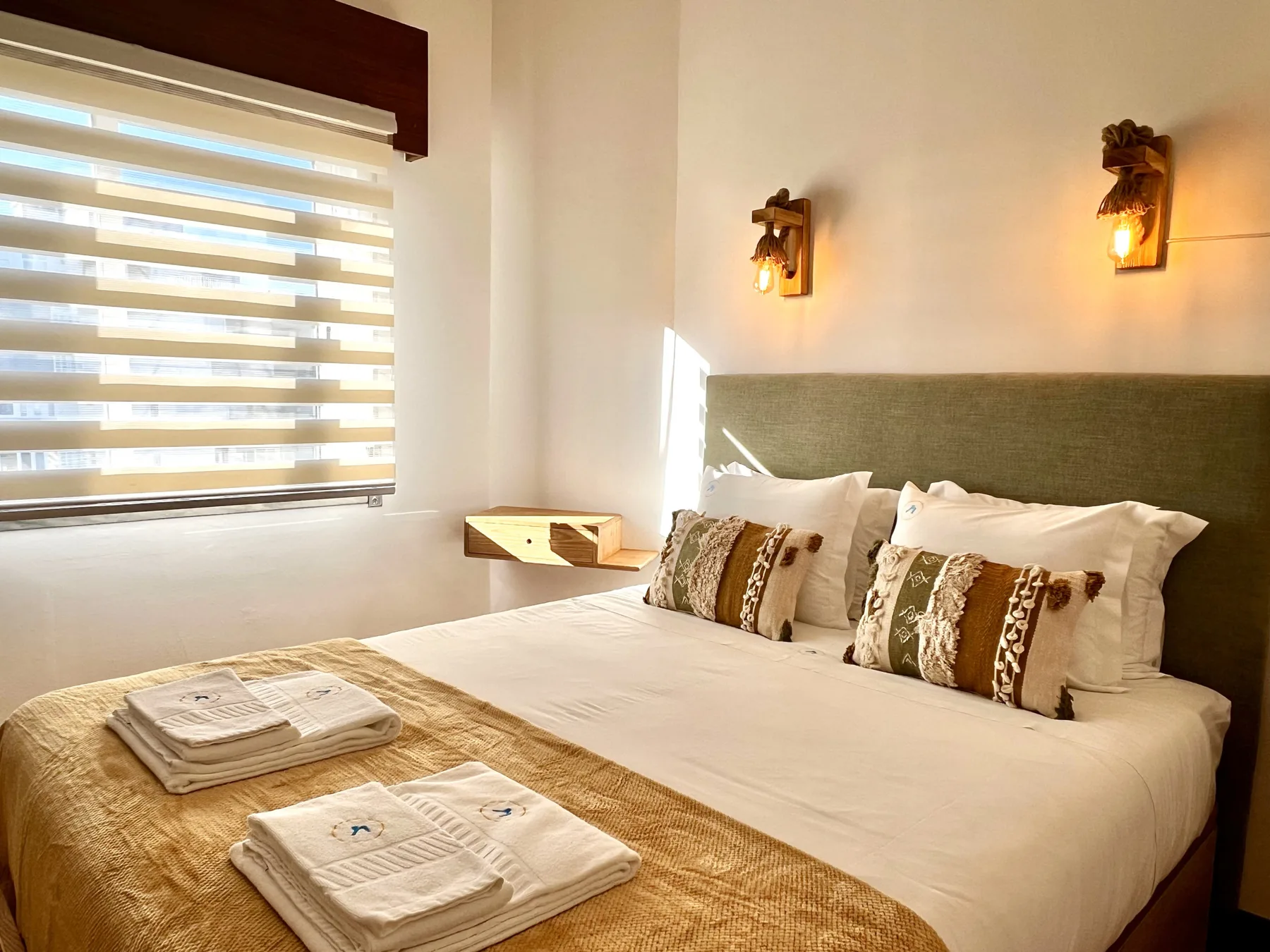 Un dormitorio con una cama bien hecha y persianas a rayas.