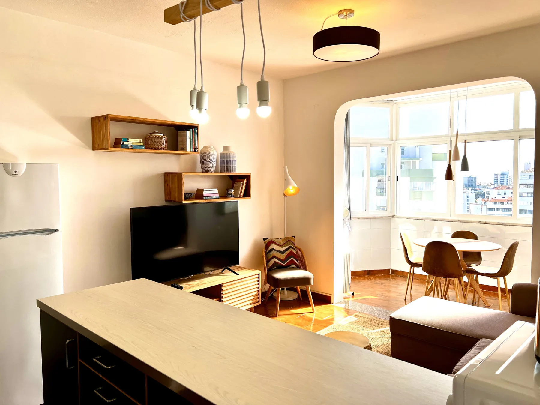 Una luminosa sala de estar y comedor con televisor y ventanas grandes.