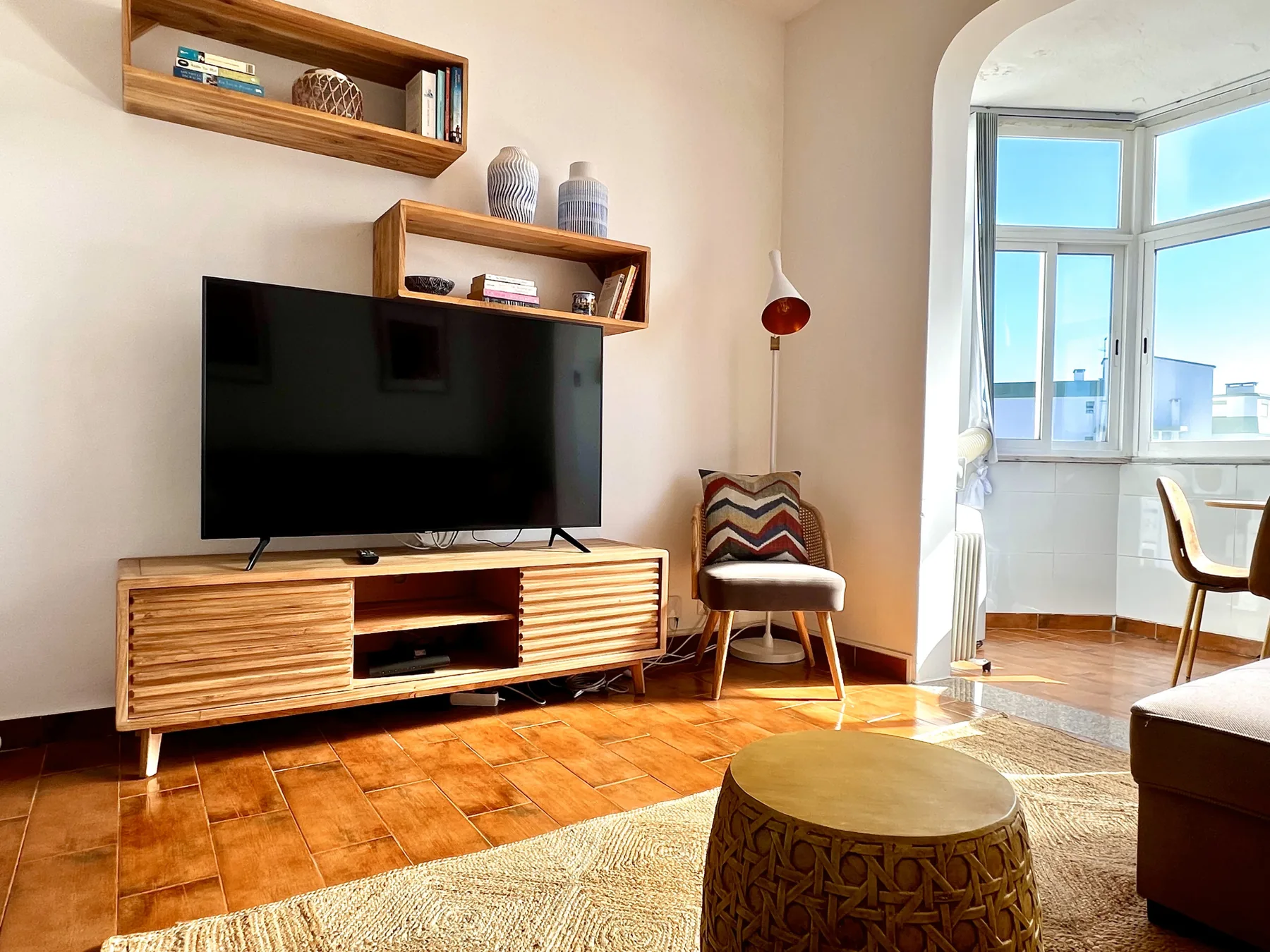 Una sala de estar con televisor, asientos y un comedor contiguo bien iluminado.