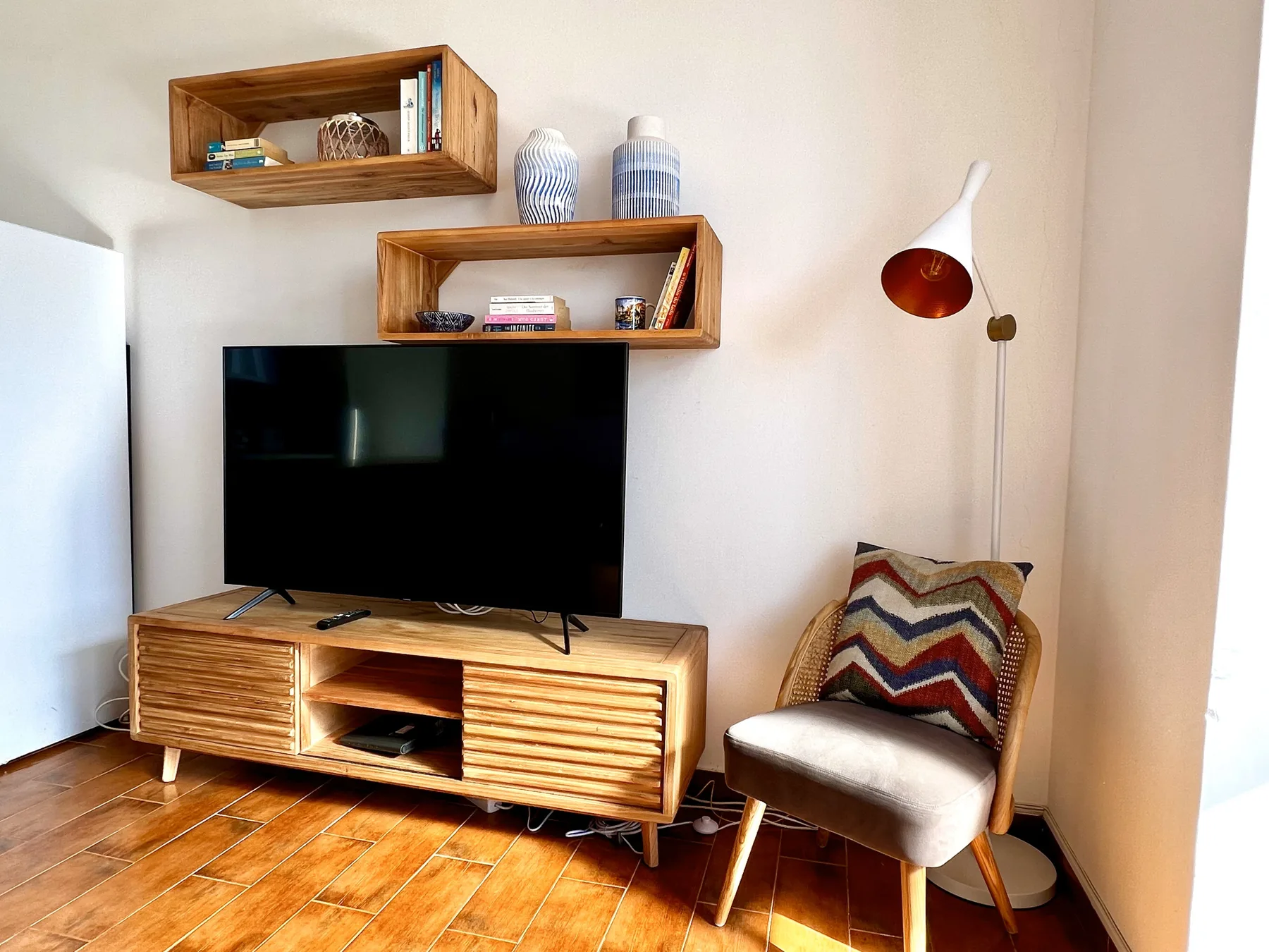 Sala de estar con televisor, estantes de madera y una silla.