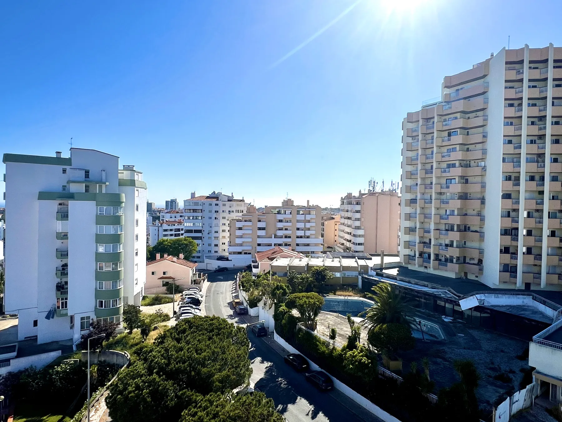 Vista urbana soleada de edificios de apartamentos, calles y zonas ajardinadas.