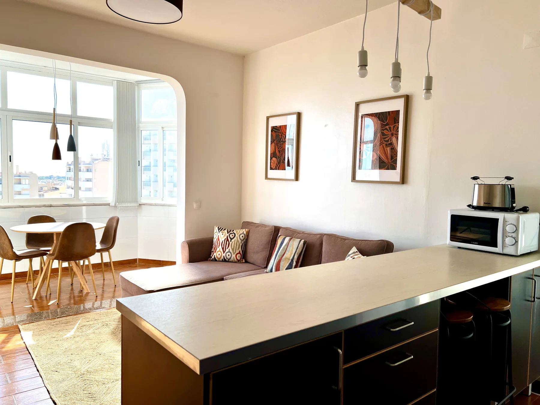 Una luminosa sala de estar y comedor diáfanos tiene asientos junto a grandes ventanas.