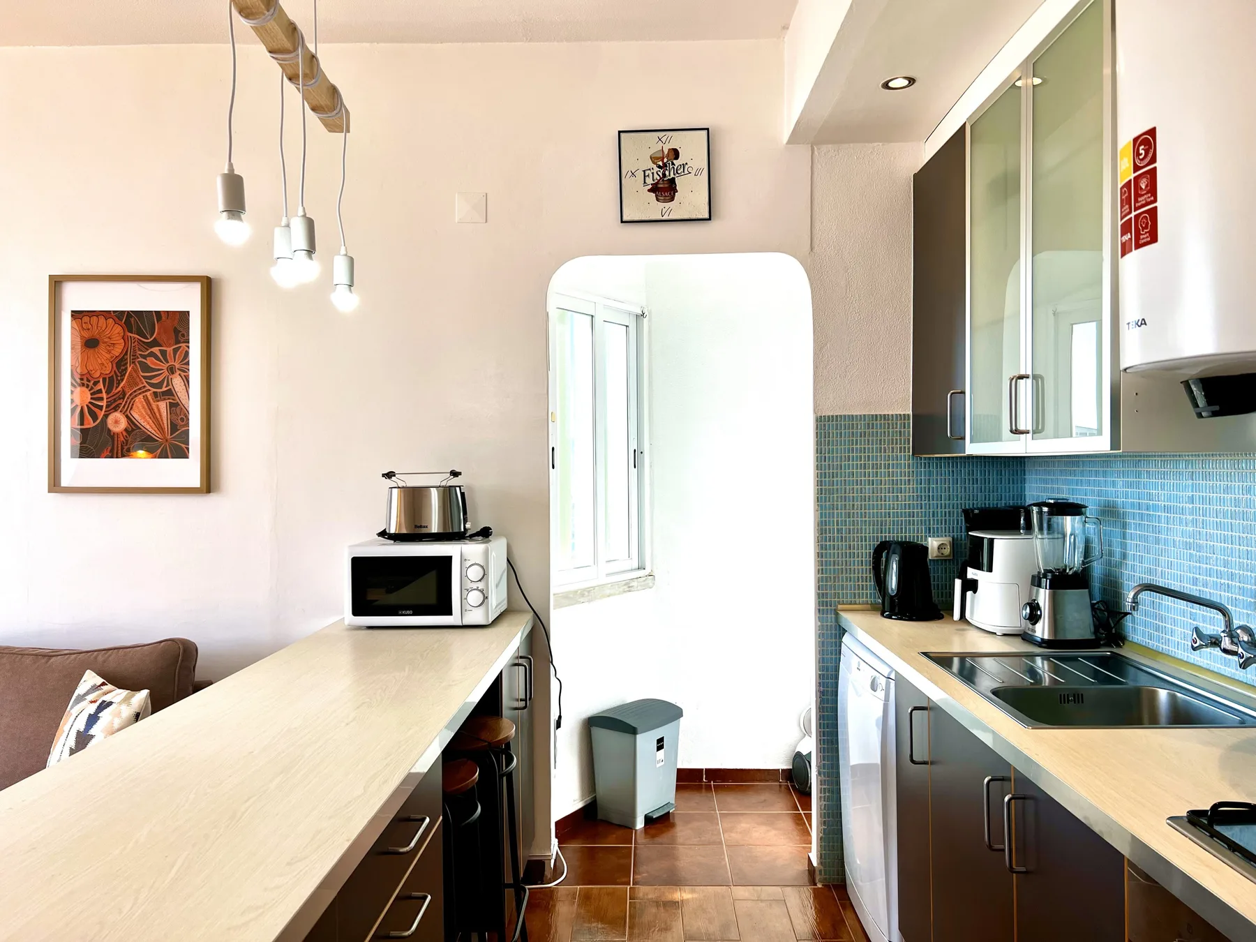 Una cocina luminosa con una barra para comer y pequeños electrodomésticos.