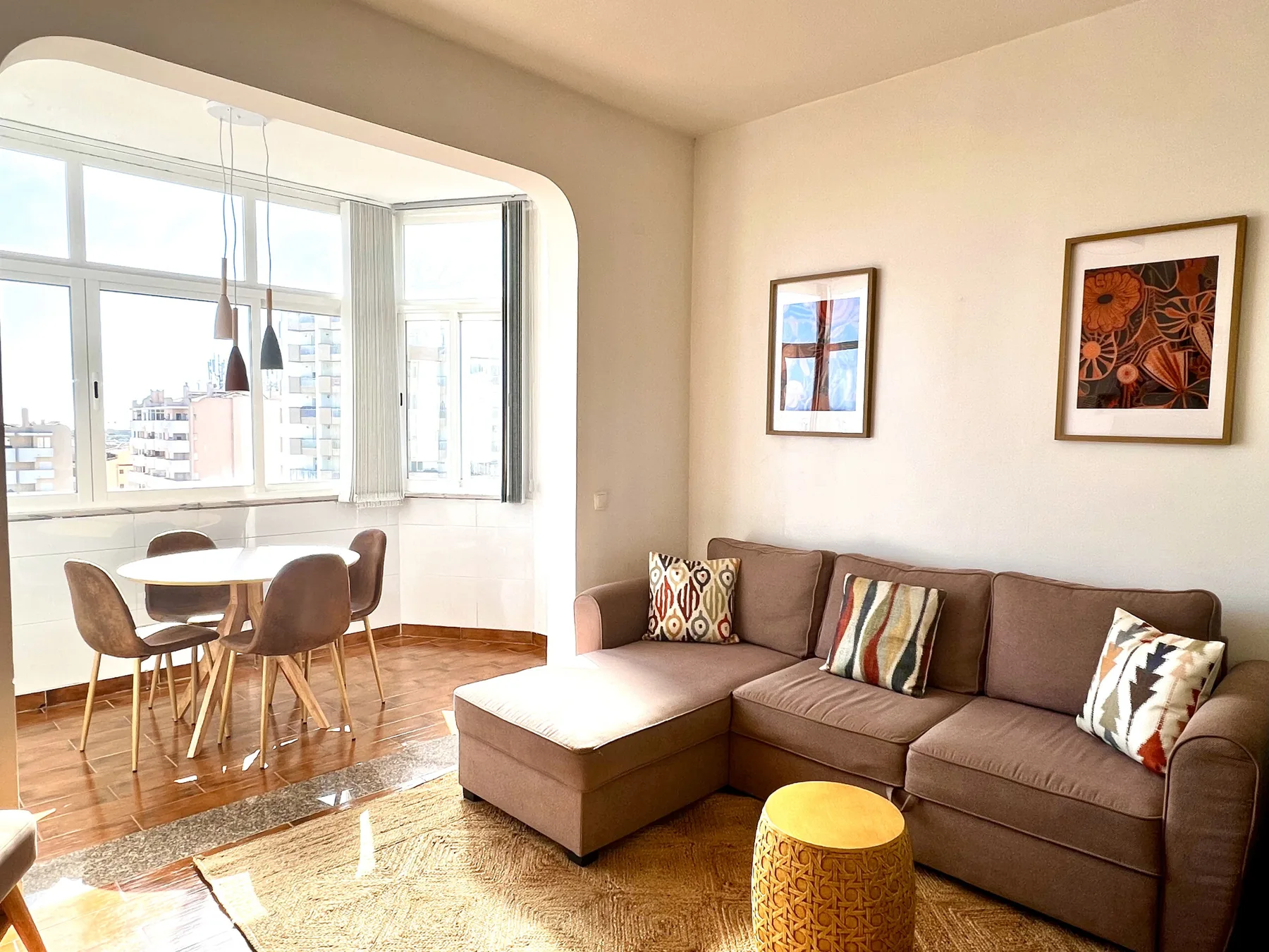 Sala de estar con asientos y comedor junto a grandes ventanas.