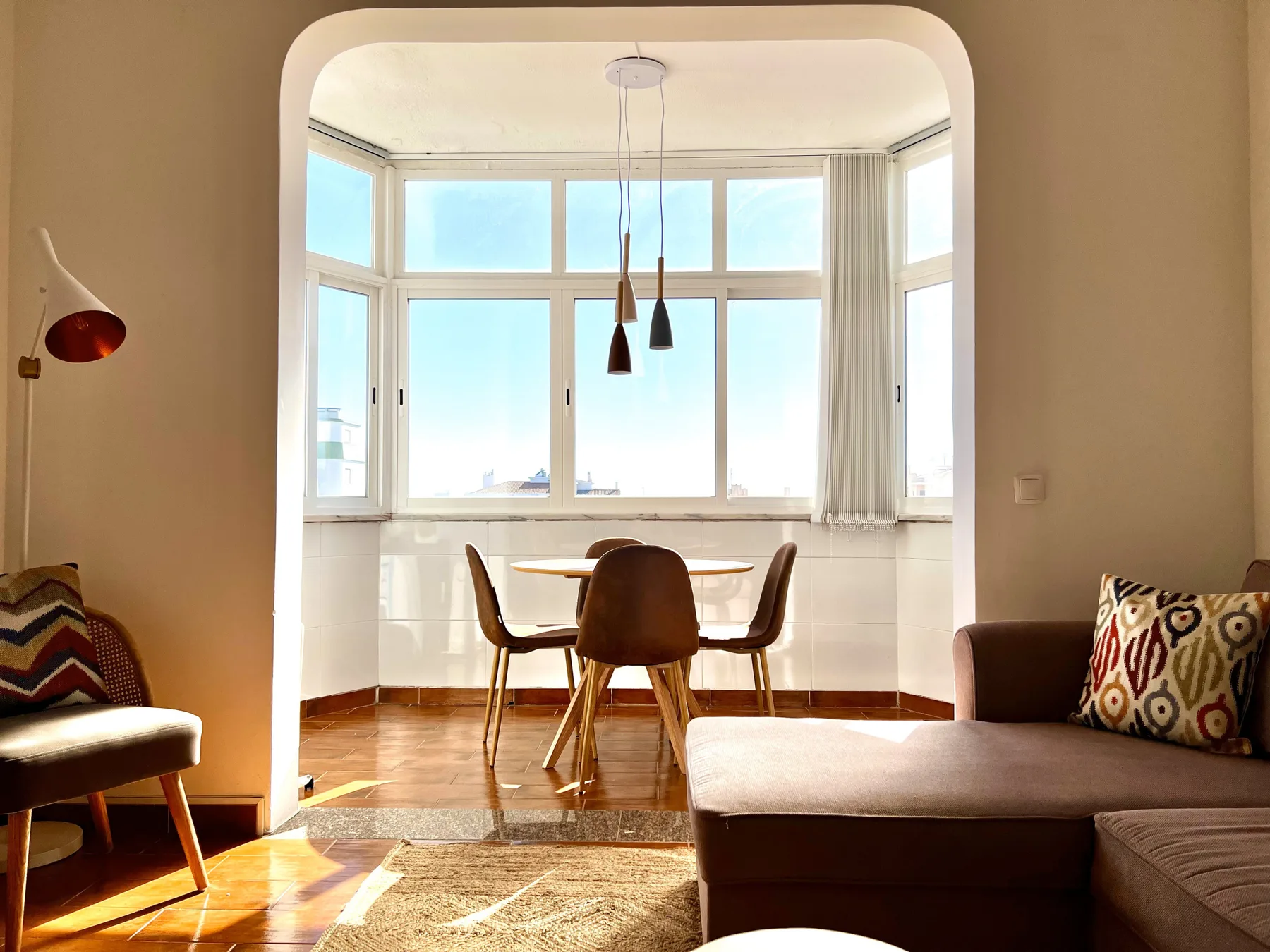 Un salón luminoso con una mesa de comedor junto a grandes ventanas.