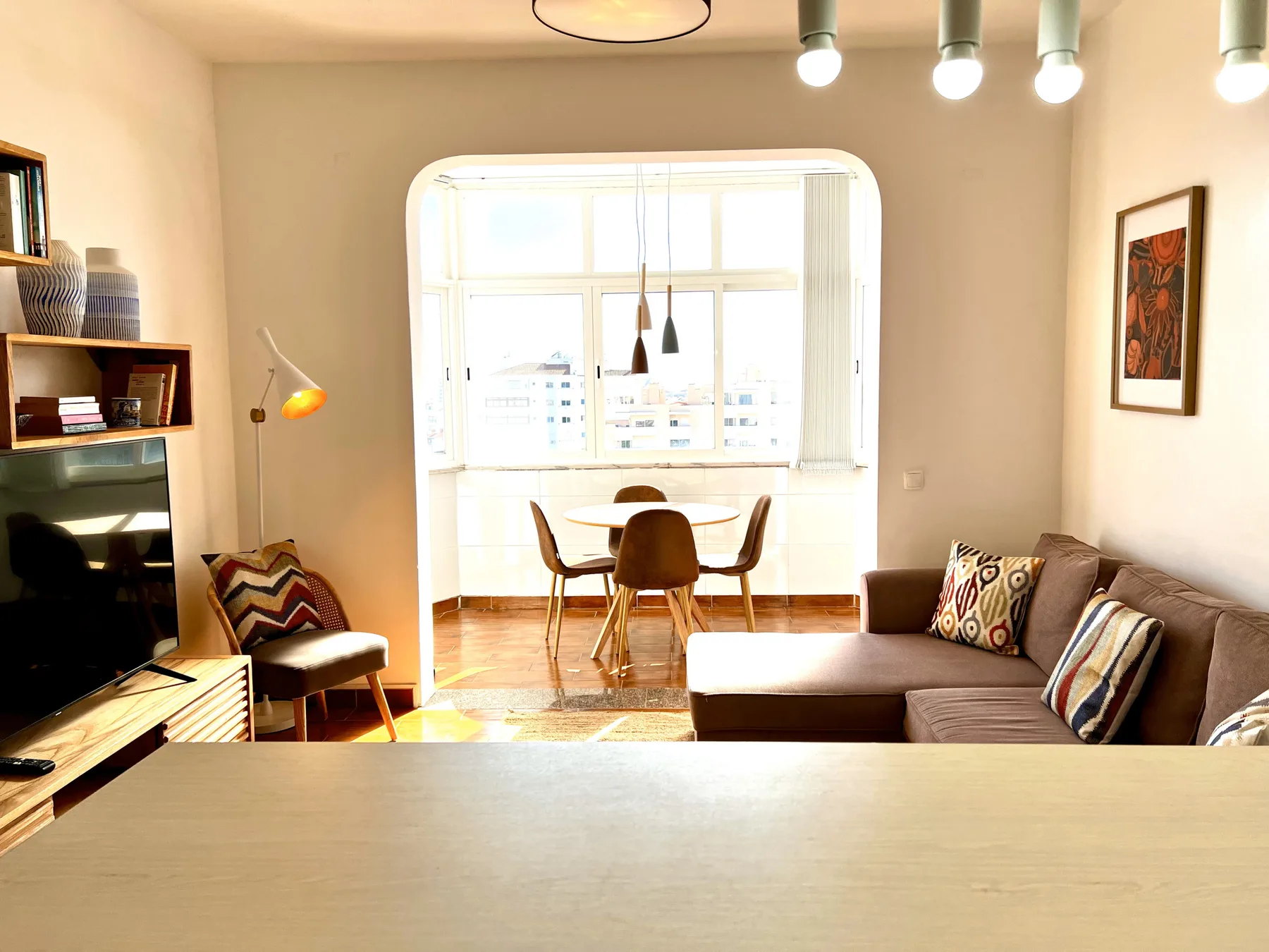 Una sala de estar con asientos y una mesa de comedor junto a una ventana luminosa.