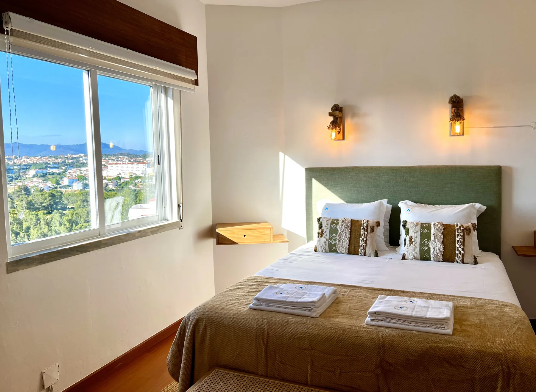 Un dormitorio con una cama junto a una gran ventana con vistas a la ciudad.