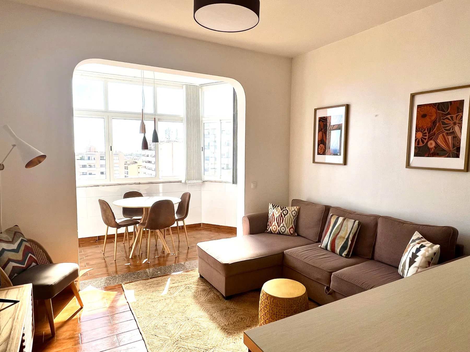 Una sala luminosa se abre a un comedor junto a grandes ventanas.