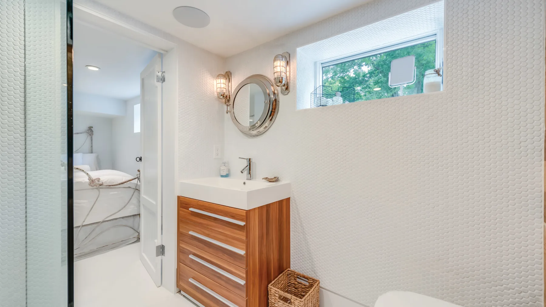 A bright bathroom with a wood vanity and a small window.