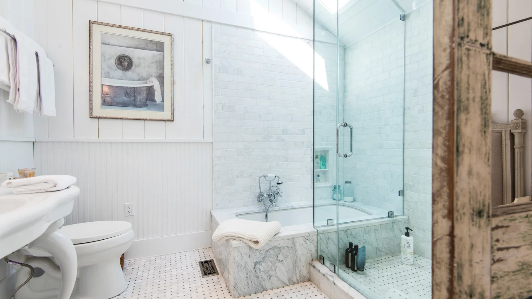 A bright bathroom with a bathtub, glass shower, and white sink.