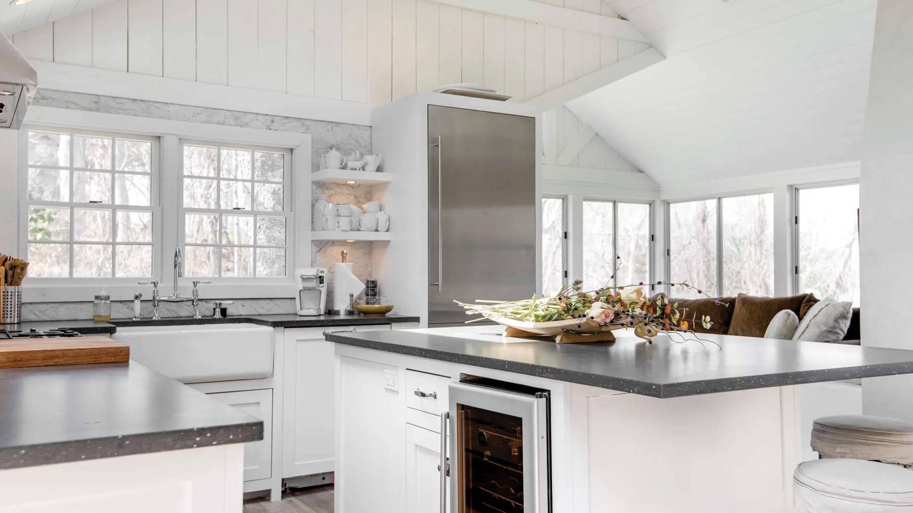 A bright kitchen with white cabinetry, broad windows, and a central island.