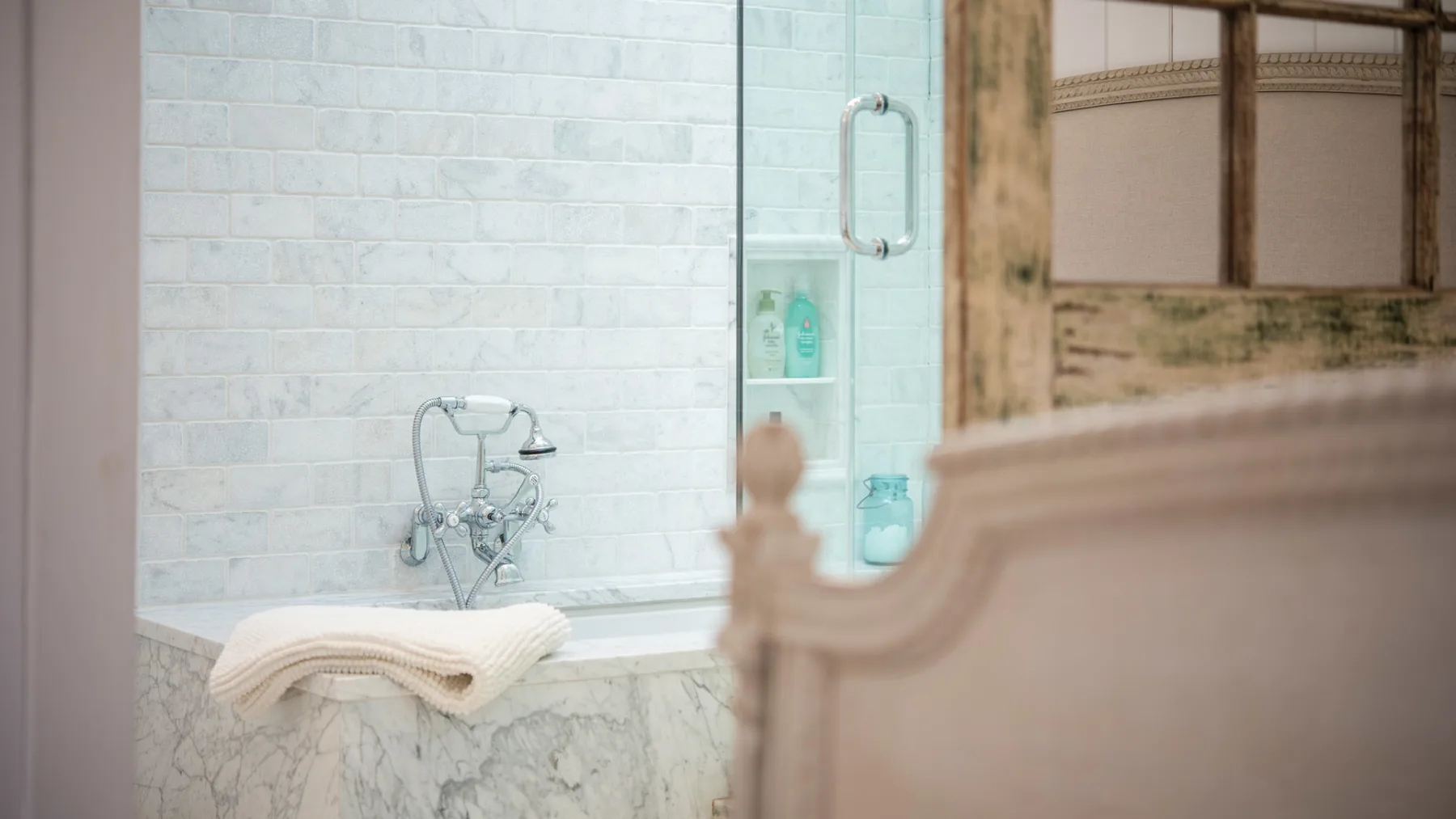 A tiled bathroom with a bathtub and glass shower screen.