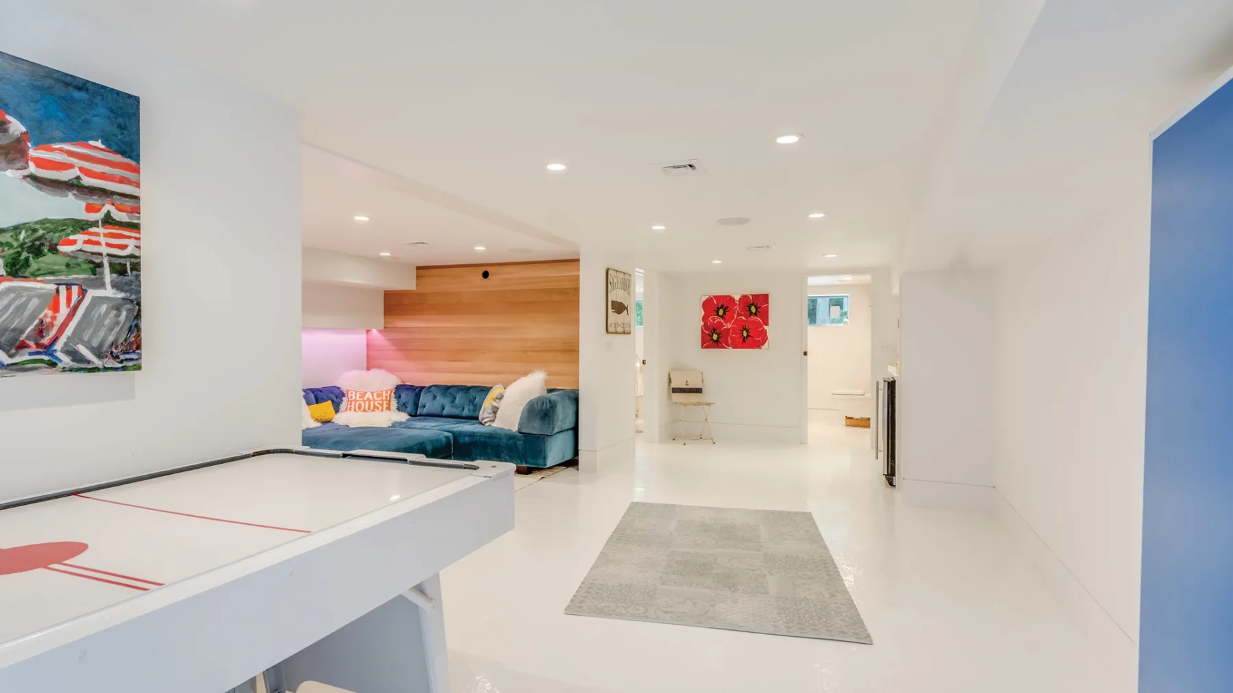 A bright game room features a ping-pong table, seating, and wall art.