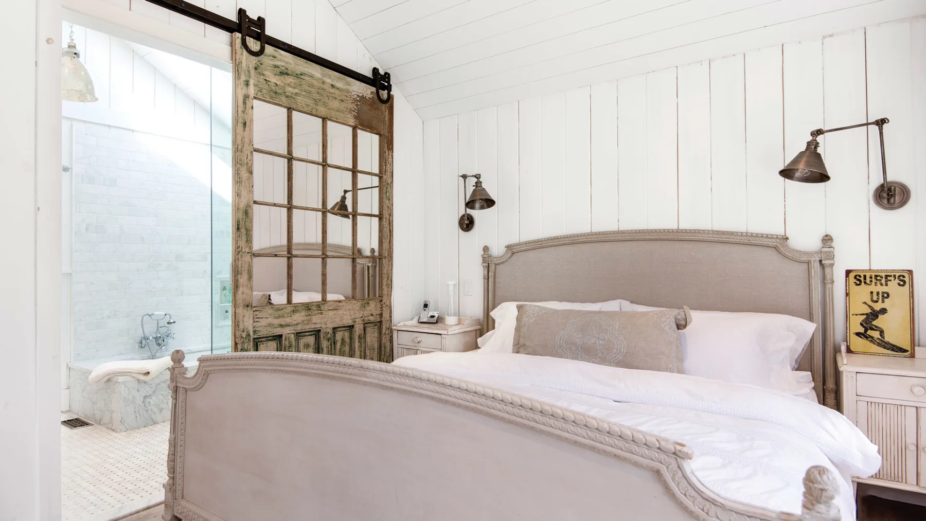 A bright bedroom with a large bed and a weathered sliding door.