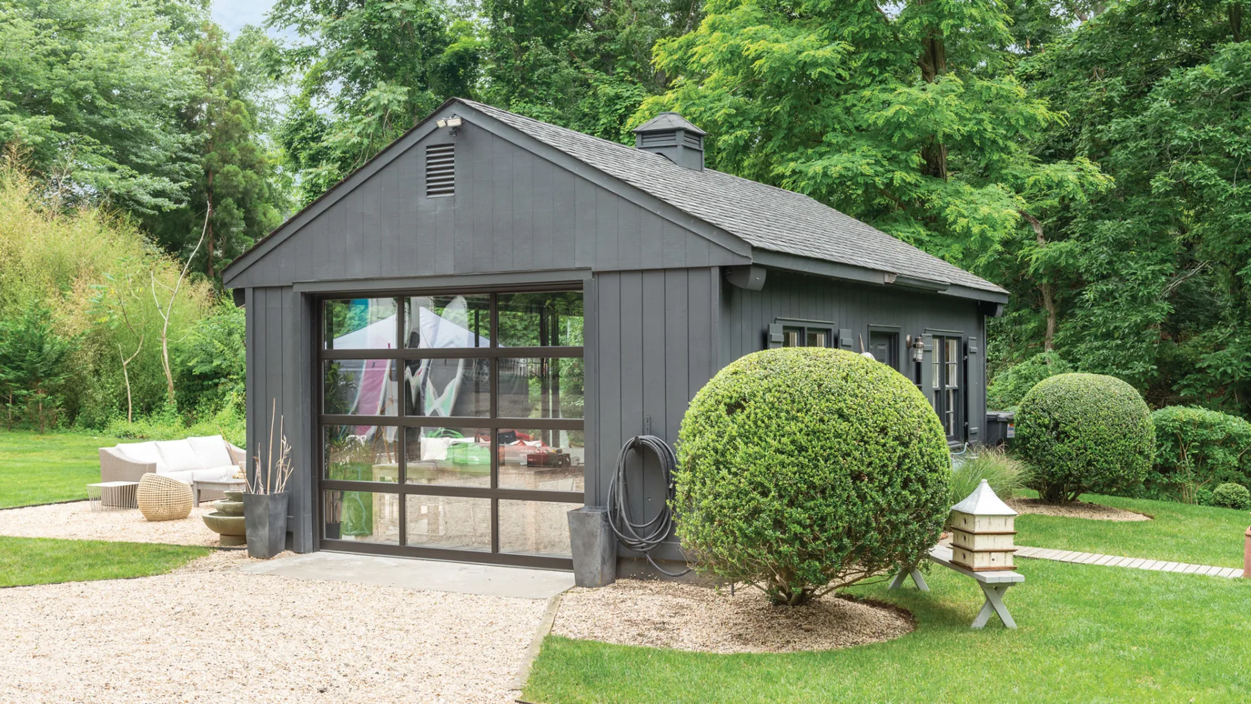A detached garage with a glass-paneled door sits beside a landscaped lawn.