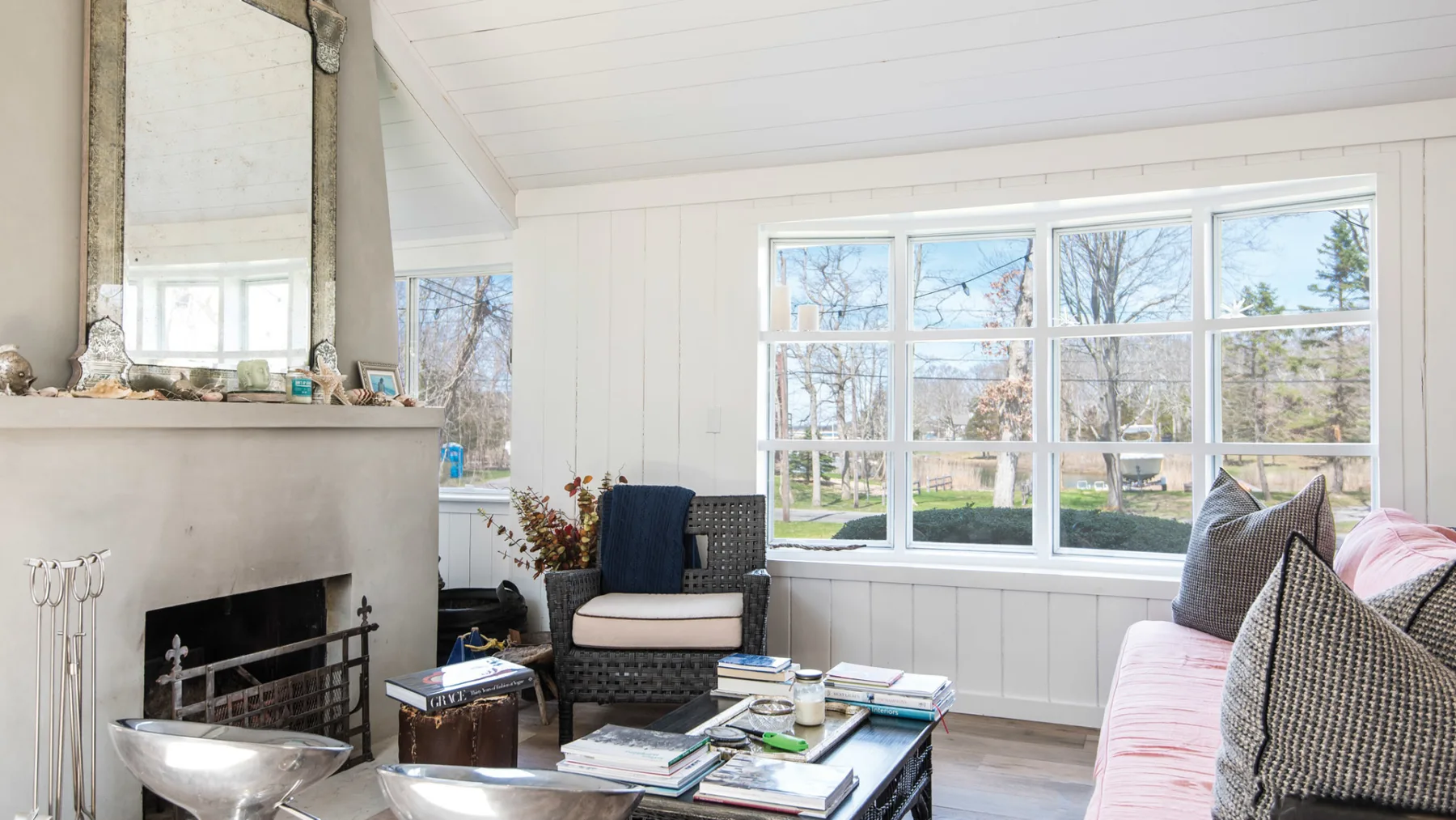 A bright living room with a fireplace, seating, and large windows.
