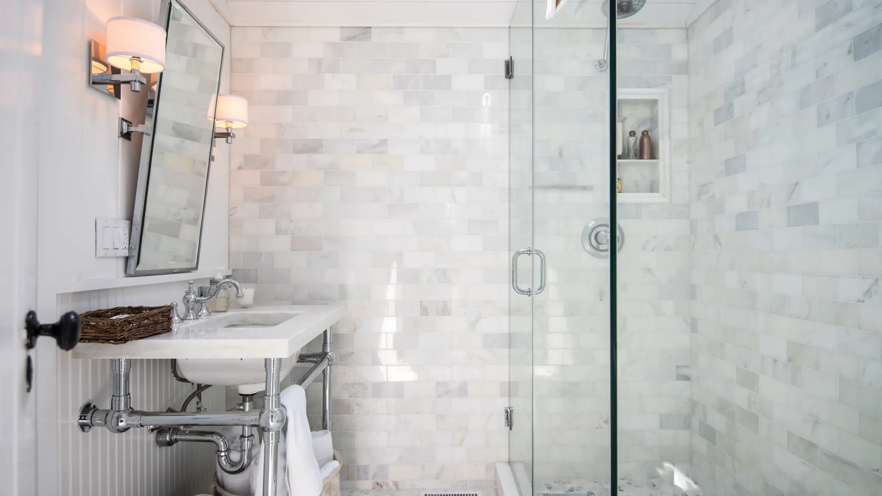A bright tiled bathroom with a sink and glass shower.