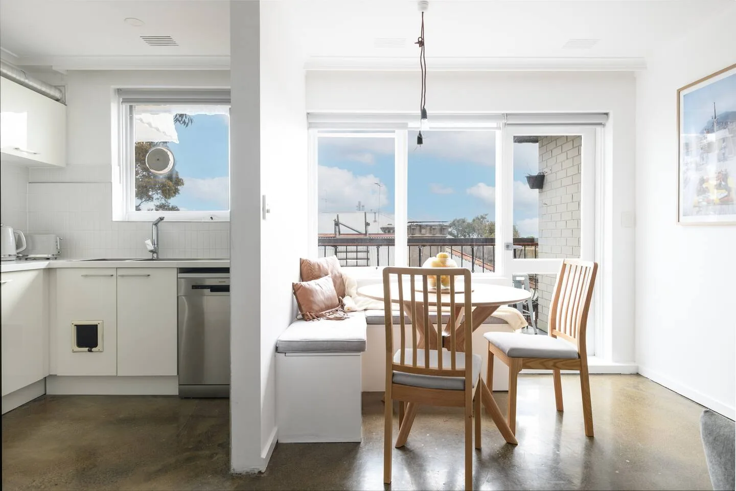 A bright kitchen and dining area opens onto a balcony through wide glass doors.
