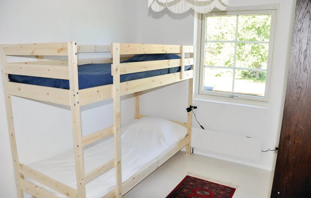 A bedroom with a wooden bunk bed and a window.