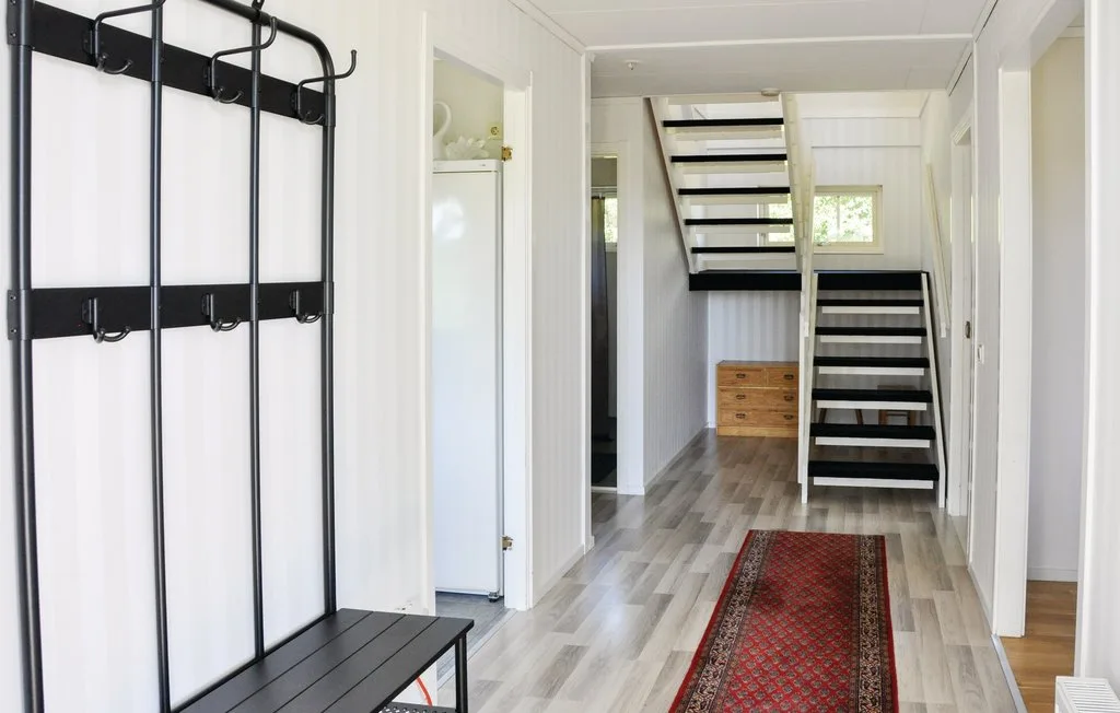 A bright hallway with a staircase and a red patterned runner.