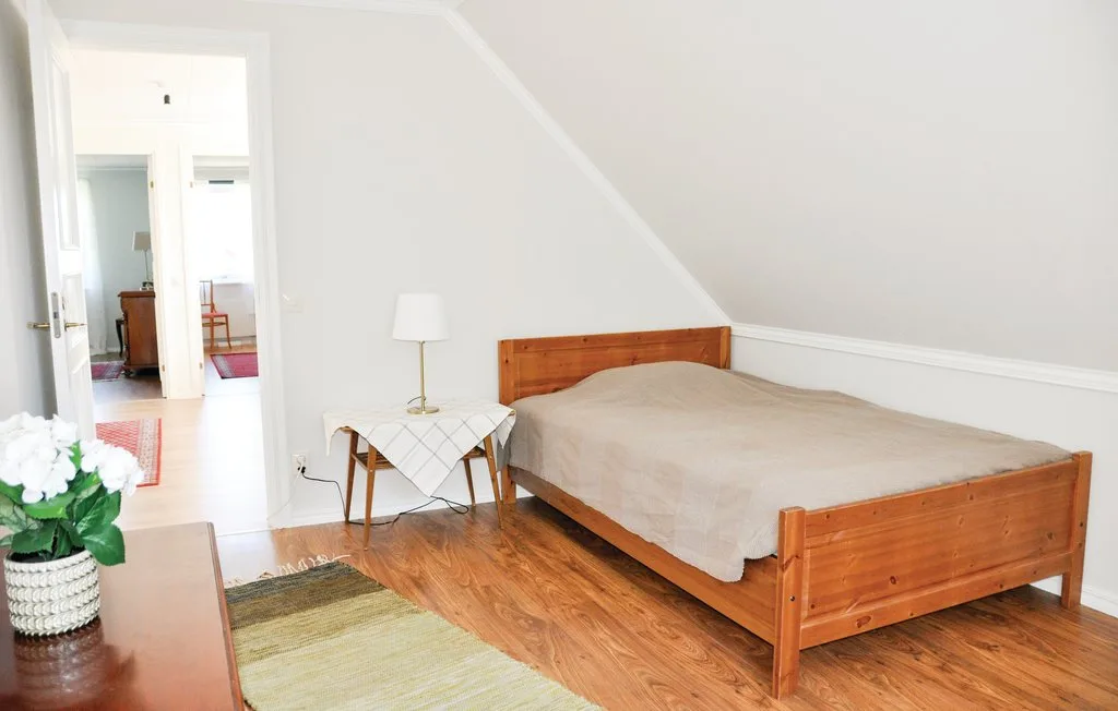 A bedroom with a wooden bed, a small table, and a lamp.