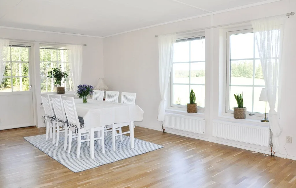 A bright dining room with a white table and chairs beside large windows.