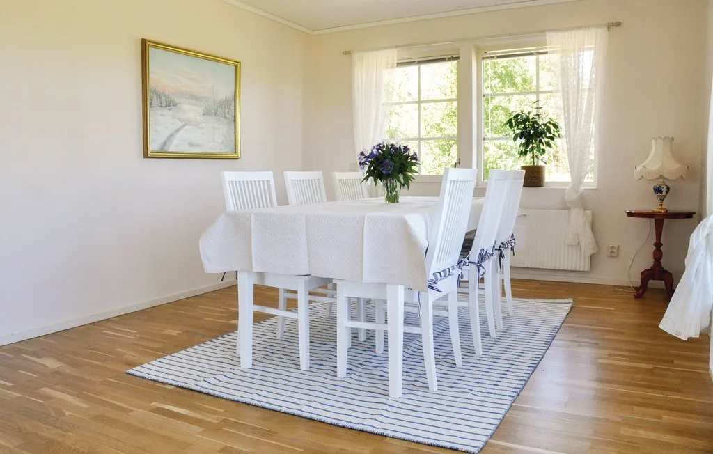A bright dining room with a set table beside large windows.